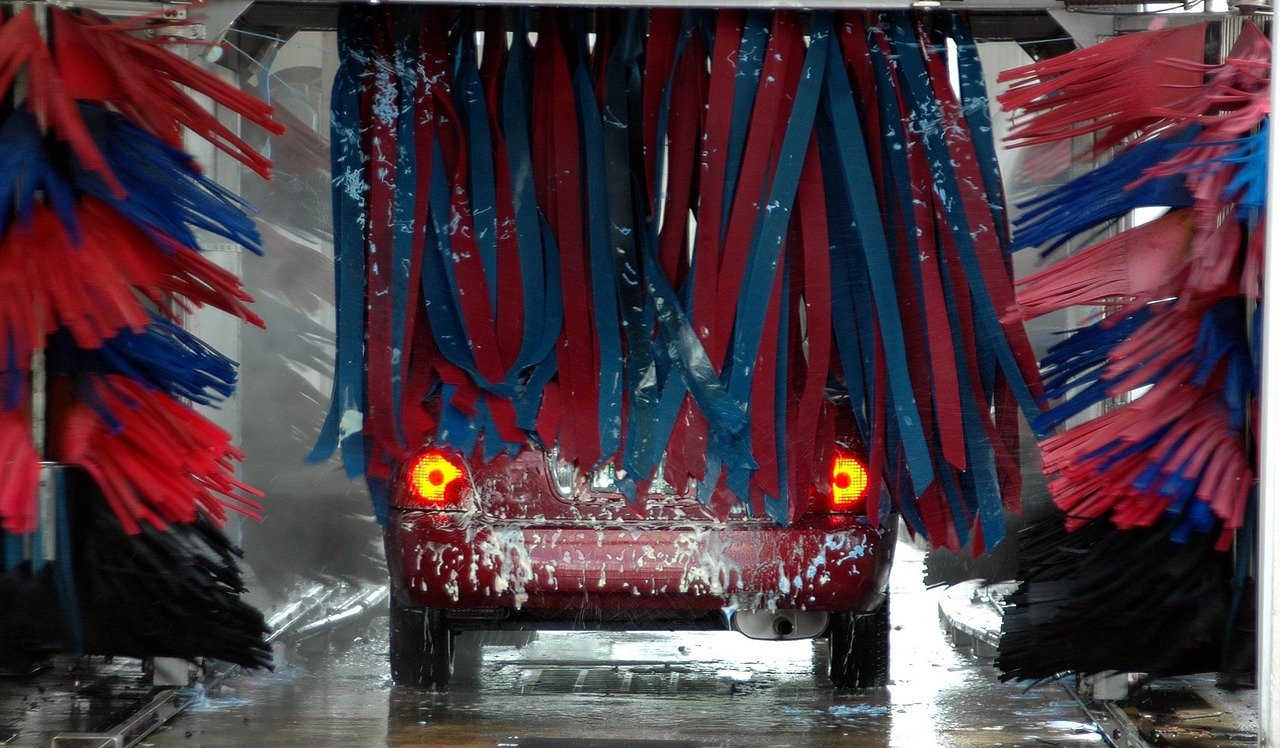 Vehicle passing through automatic car wash tunnel with colorful foam brushes at Newburgh Auto Spa